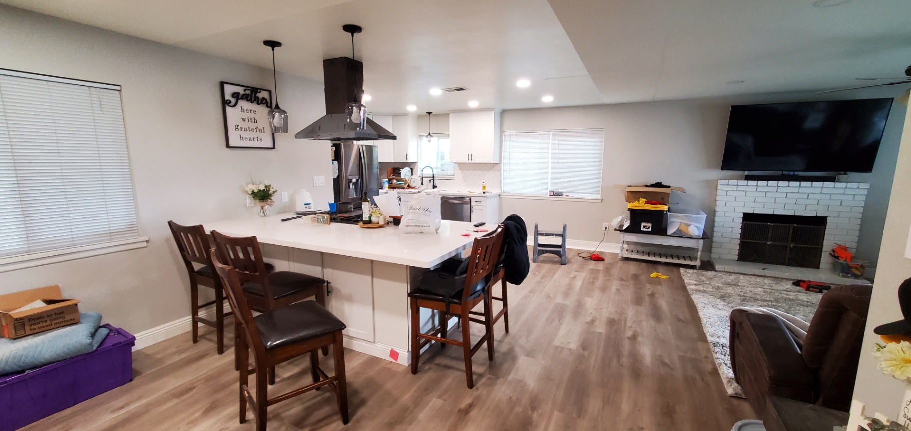 Renovated open-concept kitchen with white cabinets, quartz island, and vent hood in a Bakersfield home by Panthera Construction