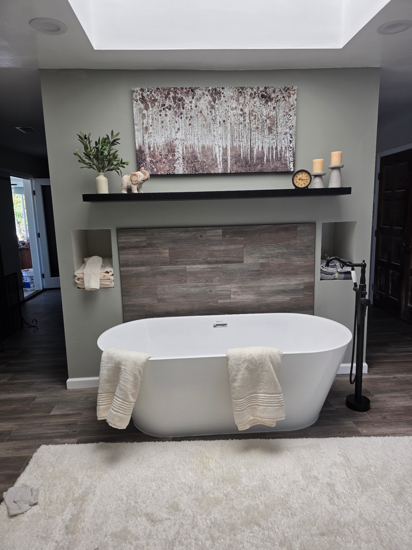 Master bathroom remodel with freestanding soaking tub, wood-tile accent wall, and matte black fixtures by Panthera Construction